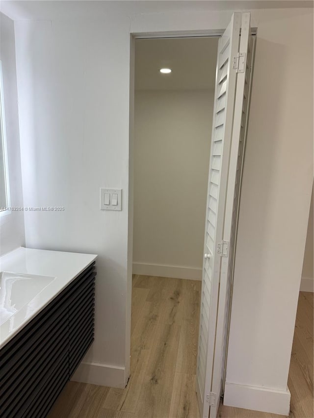 bathroom with baseboards, wood finished floors, and vanity