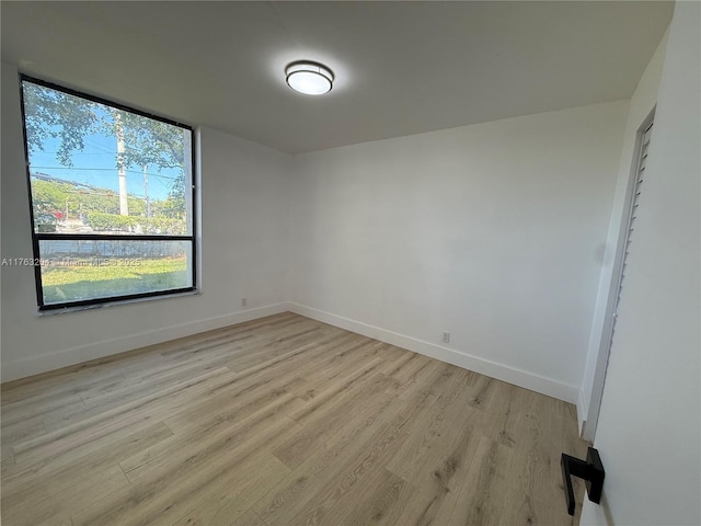 spare room featuring baseboards and light wood-style floors