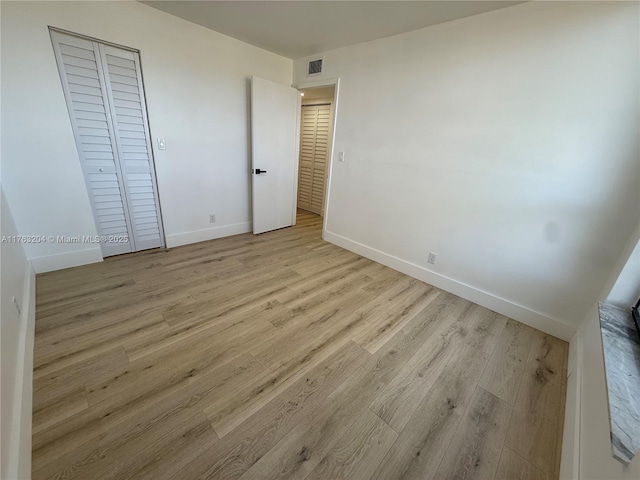 unfurnished bedroom featuring wood finished floors, visible vents, and baseboards