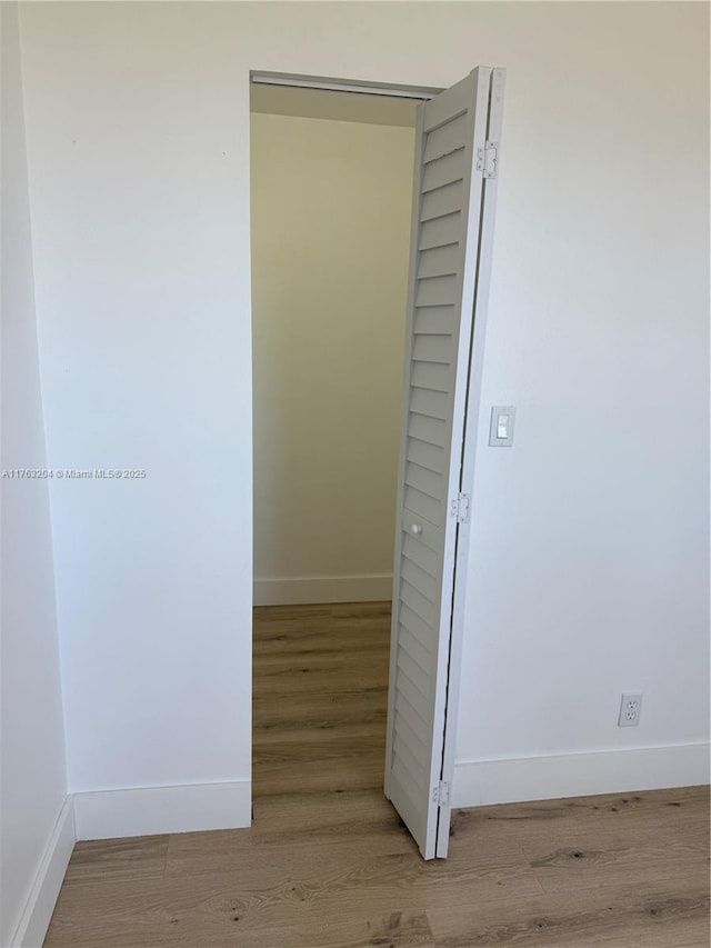 hall featuring wood finished floors and baseboards