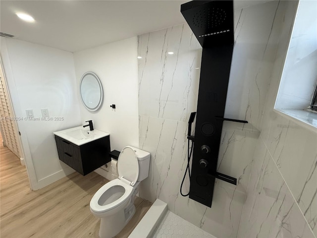 bathroom with visible vents, toilet, wood finished floors, a marble finish shower, and vanity