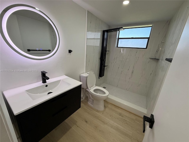 full bathroom featuring a marble finish shower, toilet, vanity, and wood finished floors