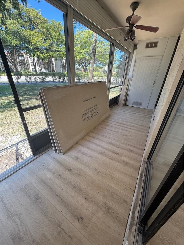 unfurnished sunroom with a ceiling fan and visible vents