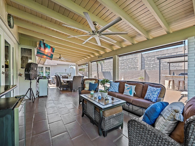 sunroom featuring beamed ceiling, ceiling fan, and wooden ceiling