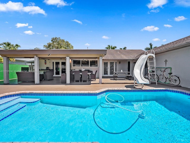 pool with french doors, an outdoor hangout area, a water slide, and a patio