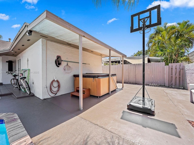 view of patio featuring a hot tub and fence