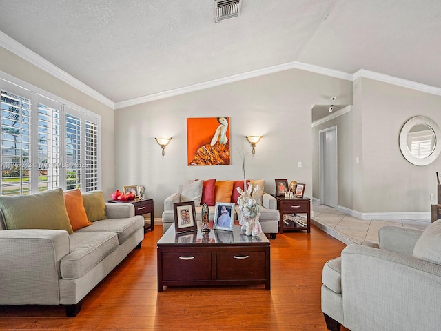 living area with visible vents, crown molding, baseboards, lofted ceiling, and wood finished floors