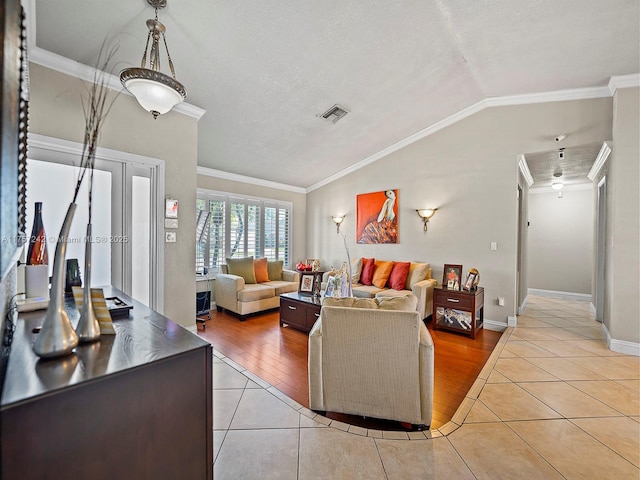 living area featuring visible vents, light tile patterned flooring, crown molding, baseboards, and vaulted ceiling