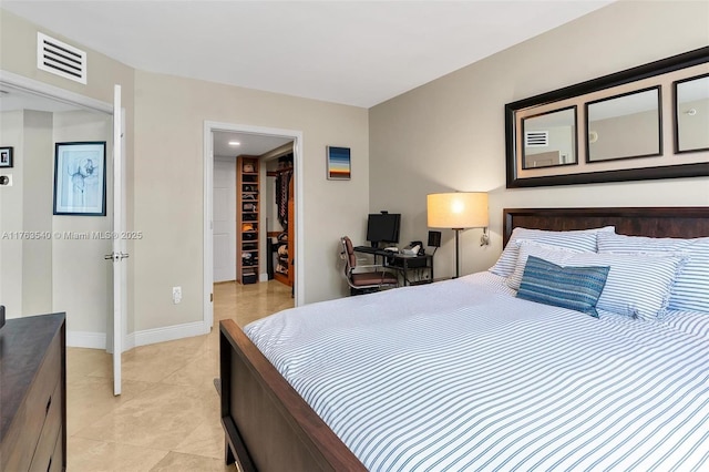 bedroom with visible vents, a walk in closet, baseboards, light tile patterned floors, and a closet