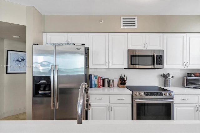 kitchen with light countertops, white cabinets, visible vents, and stainless steel appliances