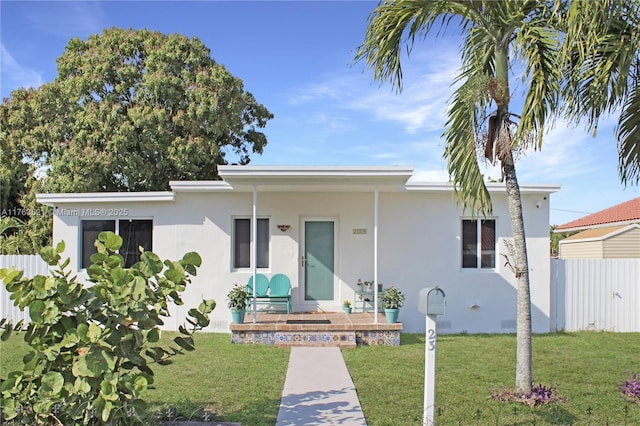 view of front of property featuring stucco siding, a front lawn, and fence