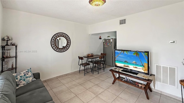 living area featuring light tile patterned floors, visible vents, and a textured ceiling