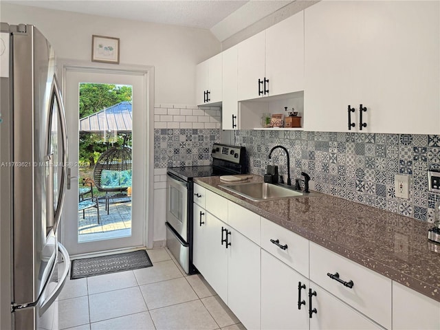 kitchen featuring lofted ceiling, light tile patterned flooring, a sink, appliances with stainless steel finishes, and backsplash