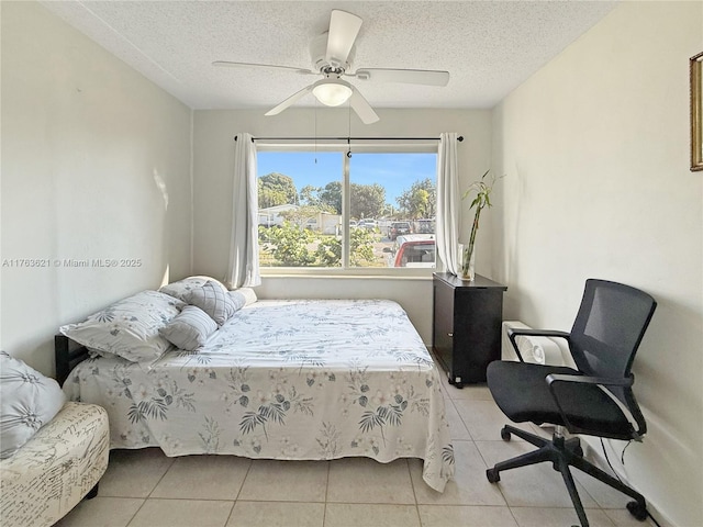 bedroom featuring ceiling fan, light tile patterned flooring, and a textured ceiling