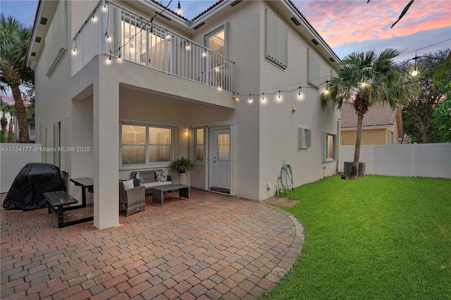 rear view of property featuring stucco siding, a lawn, a fenced backyard, and a patio area