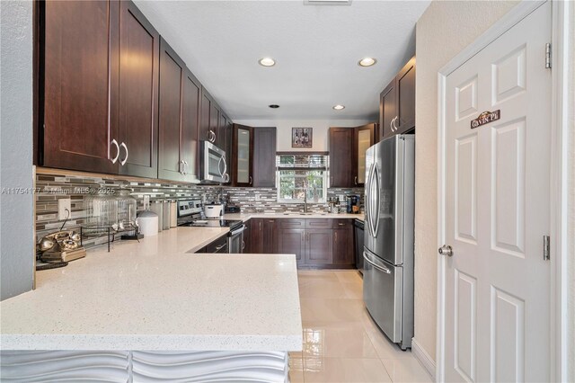 7546 NW 18th Dr, Pembroke Pines, FL 33024 - kitchen with light stone countertops, recessed lighting, dark brown cabinetry, tasteful backsplash, and appliances with stainless steel finishes