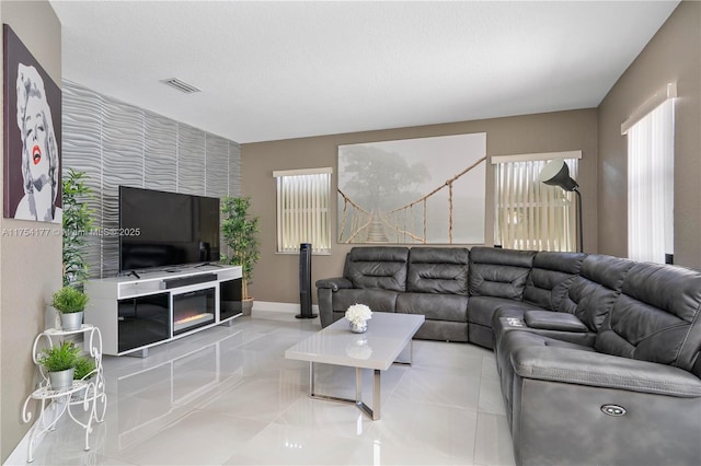 living room with visible vents, baseboards, an accent wall, and tile patterned flooring