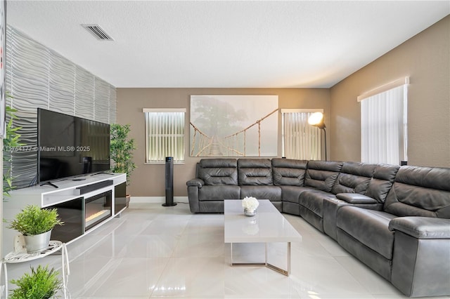 living room with light tile patterned floors, visible vents, baseboards, and a textured ceiling