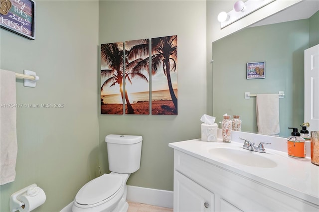 bathroom with toilet, vanity, and baseboards