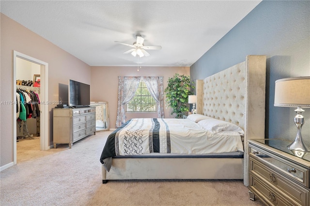 bedroom with light carpet, ceiling fan, a walk in closet, and a closet