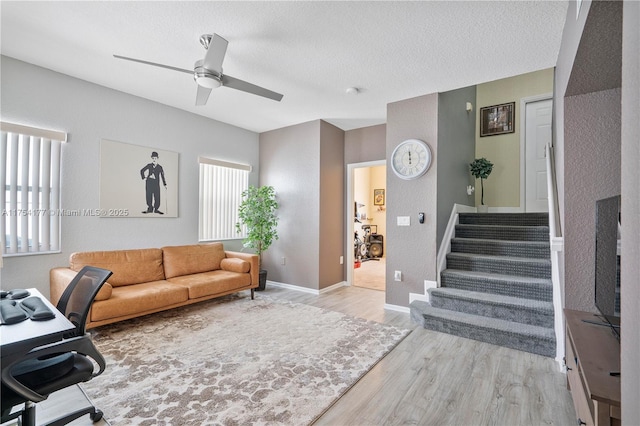 office with light wood finished floors, baseboards, a textured ceiling, and a ceiling fan