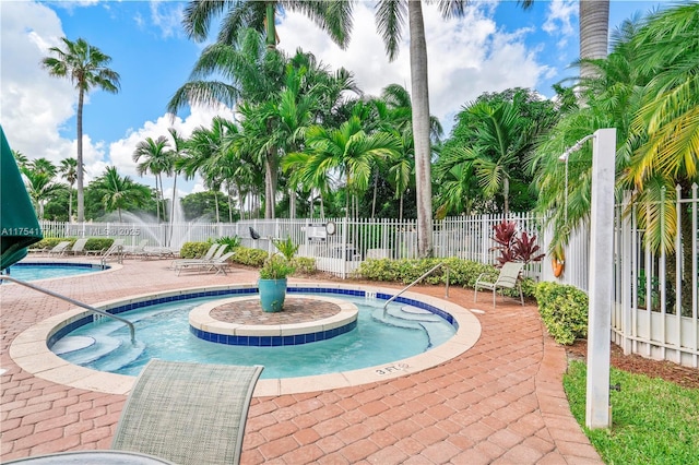 community pool with a patio area and fence