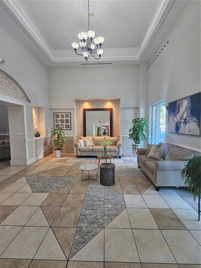 tiled living area with a tray ceiling, a towering ceiling, and a chandelier