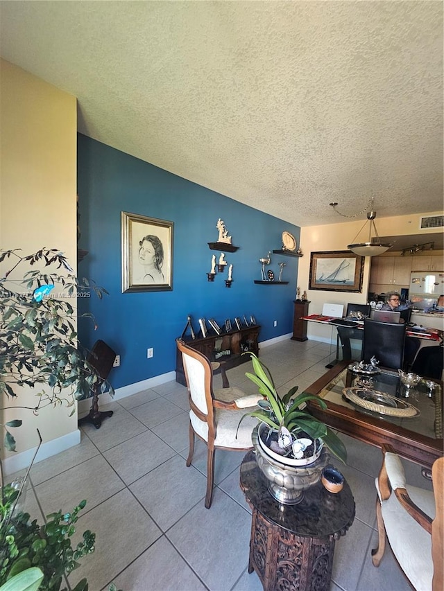 tiled living area featuring baseboards, visible vents, and a textured ceiling