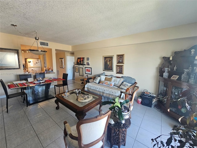 living area with visible vents, a textured ceiling, and tile patterned flooring