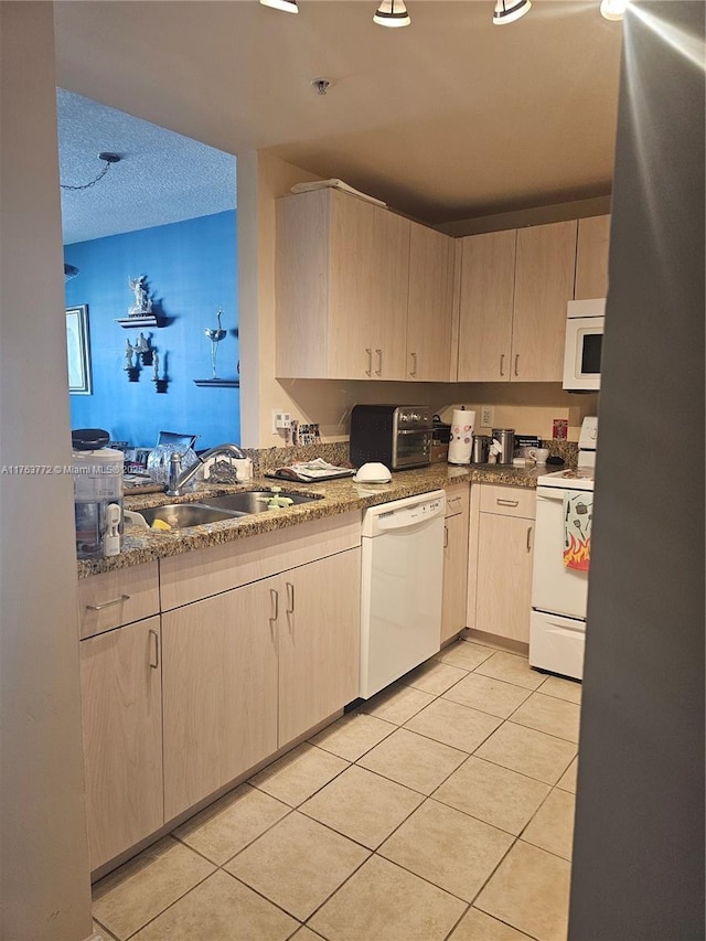 kitchen with light brown cabinets, light tile patterned flooring, white appliances, a textured ceiling, and a sink