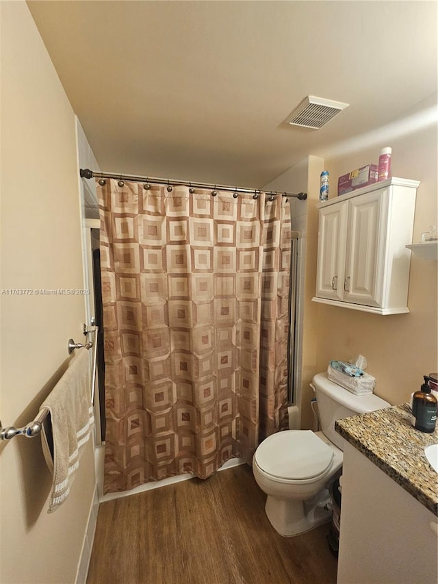 bathroom featuring visible vents, toilet, wood finished floors, a shower with shower curtain, and vanity