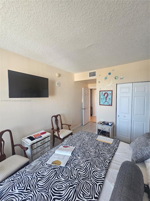 living area featuring light tile patterned floors, visible vents, and a textured ceiling