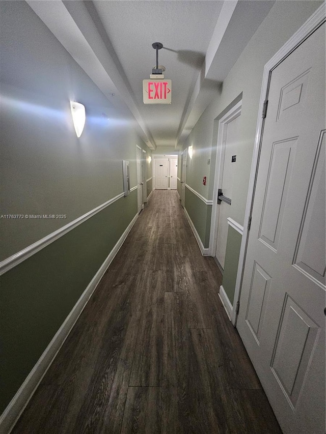 corridor featuring baseboards and wood finished floors