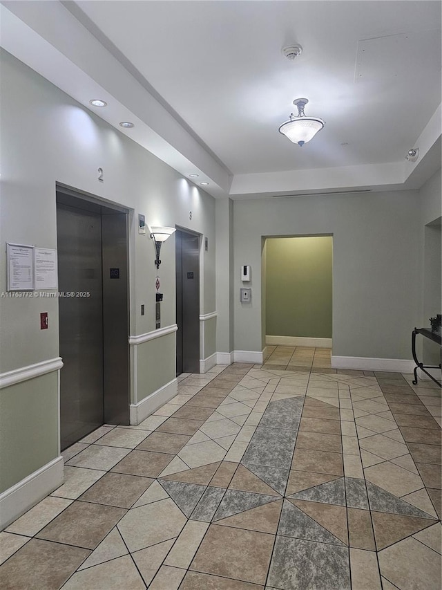 hall with tile patterned floors, elevator, and baseboards