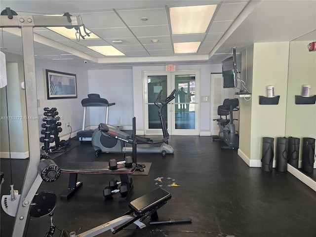 gym with a drop ceiling and baseboards