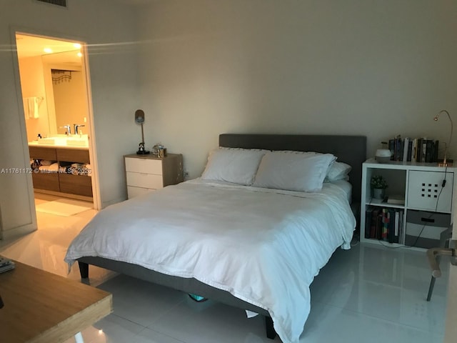 bedroom featuring light tile patterned floors, ensuite bathroom, and a sink