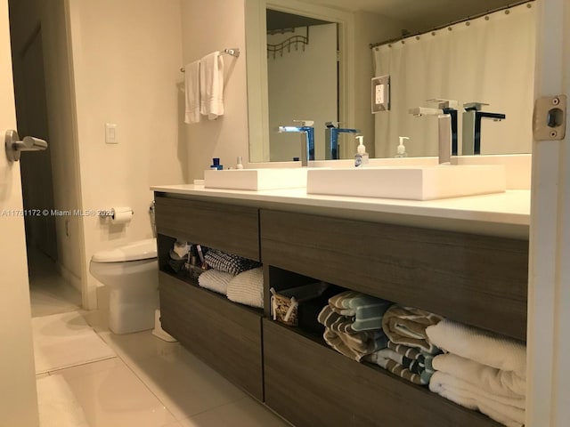 bathroom with toilet, vanity, and tile patterned flooring