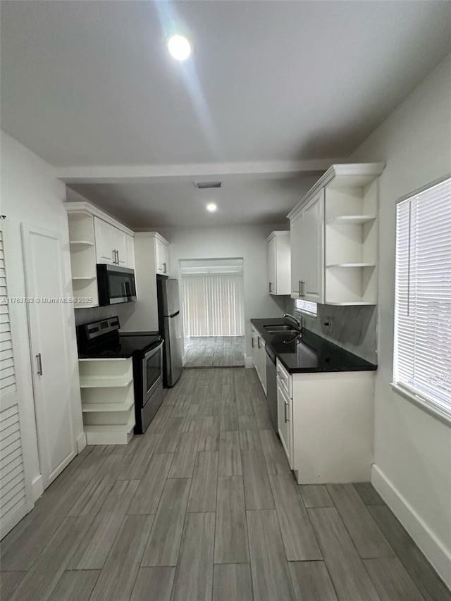 kitchen with open shelves, a sink, stainless steel appliances, white cabinetry, and dark countertops