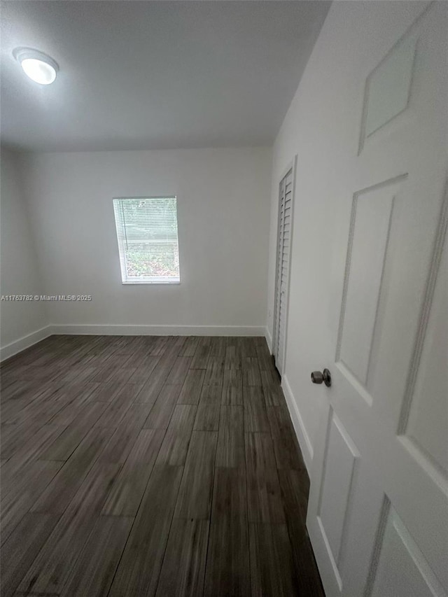 spare room featuring dark wood finished floors and baseboards