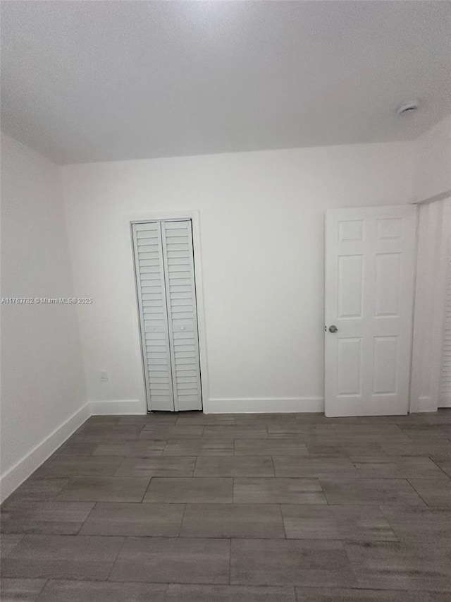 empty room featuring wood finish floors, baseboards, and a textured ceiling