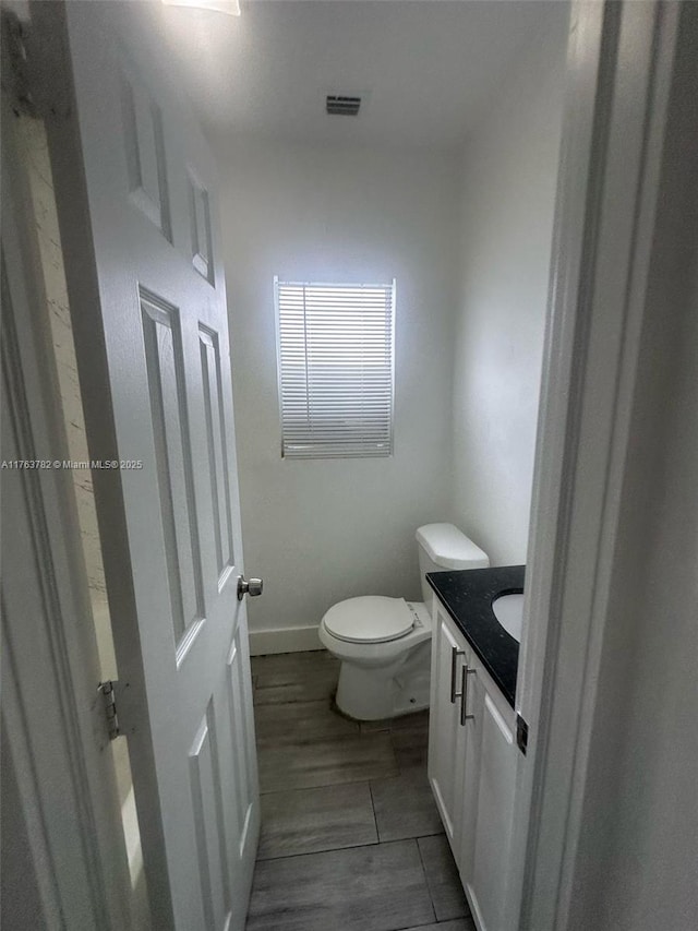 bathroom with visible vents, baseboards, toilet, and vanity