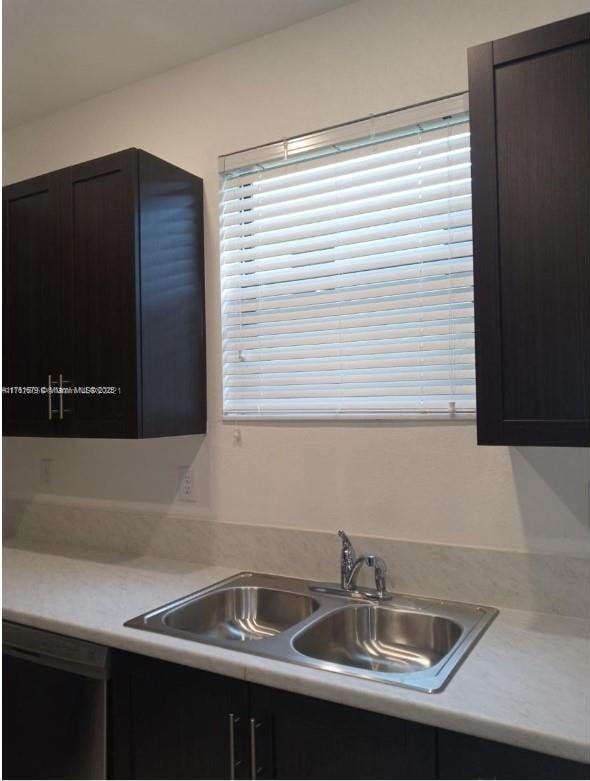 kitchen featuring dishwasher, light countertops, and a sink