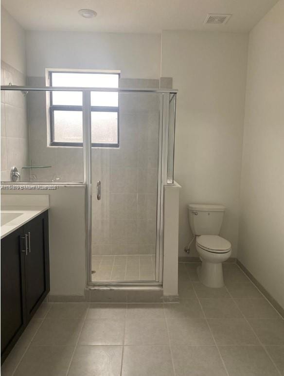 bathroom with tile patterned floors, a shower stall, toilet, and vanity