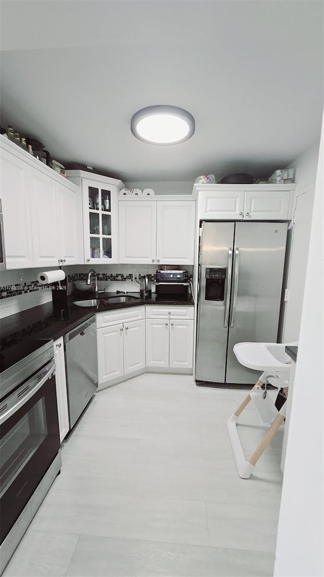 2821 N Miami Beach Blvd Unit 4F, North Miami Beach, FL 33160 - kitchen featuring appliances with stainless steel finishes, white cabinets, glass insert cabinets, and dark countertops