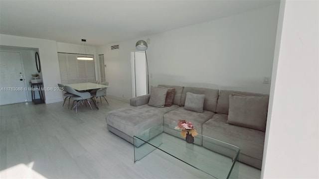 living area with wood finished floors, visible vents, and baseboards