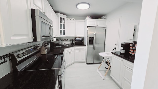 2821 N Miami Beach Blvd Unit 4F, North Miami Beach, FL 33160 - kitchen with stainless steel appliances, white cabinetry, decorative backsplash, and glass insert cabinets