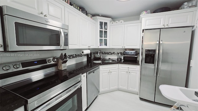 2821 N Miami Beach Blvd Unit 4F, North Miami Beach, FL 33160 - kitchen featuring appliances with stainless steel finishes, white cabinets, glass insert cabinets, and decorative backsplash