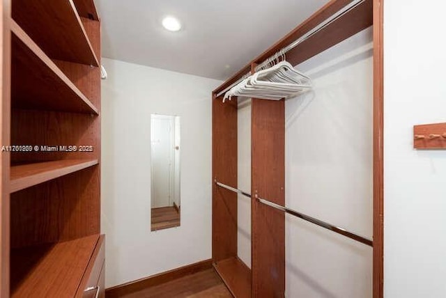 walk in closet with wood finished floors