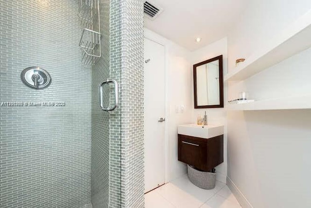 bathroom featuring visible vents, baseboards, tiled shower, tile patterned floors, and vanity