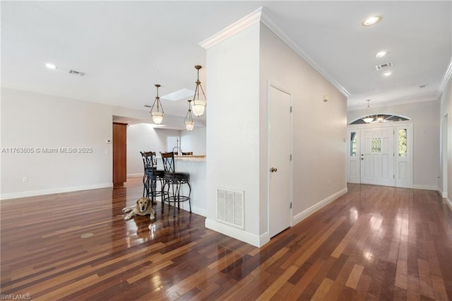 hall with hardwood / wood-style floors, visible vents, and ornamental molding